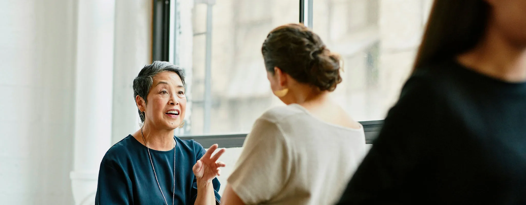 Two women talking in an office breakroom.