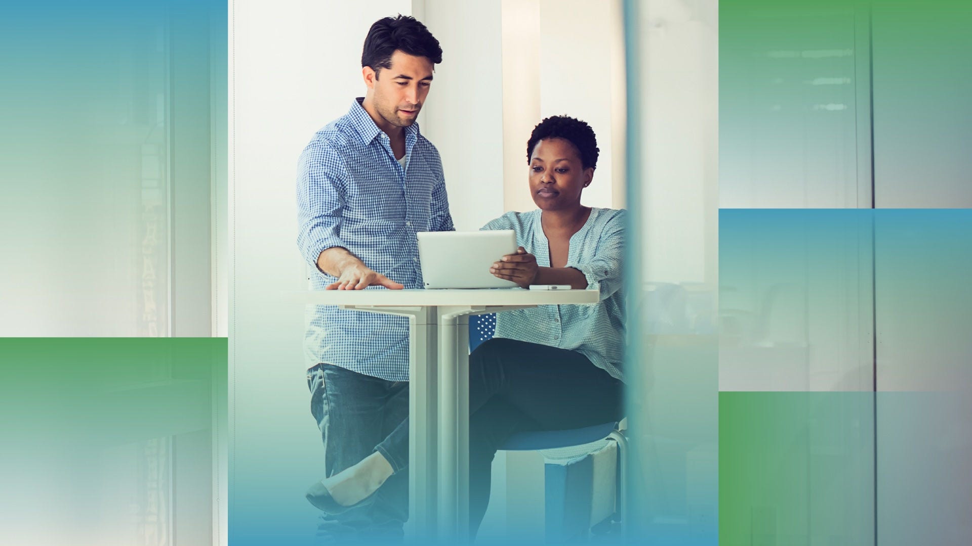 A man and woman are looking at a mobile tablet together in an office setting